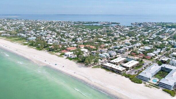 Vista aérea de una zona residencial costera con playa, casas y un gran hotel de varias construcciones.