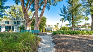 A pathway leading to a building with a porch and a bench.