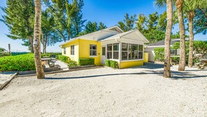 A yellow building with a covered patio and a gravel driveway.