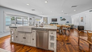 A spacious kitchen with a large island, wooden flooring, and a view to the outside. - North End Home, 5 Houses to Beach! Near Pine Ave! (Anna Maria)