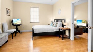 Une chambre à coucher avec un lit, une chaise, un téléviseur et un ventilateur de plafond.