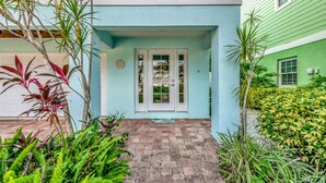 Une maison à l’extérieur bleu clair, avec une porte de garage blanche et un chemin de briques menant à une entrée à double porte.