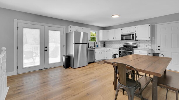 Una cocina moderna con armarios blancos, electrodomésticos de acero inoxidable y una mesa de comedor de madera.