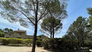 Un edificio de piedra con tejado de baldosas, rodeado de árboles y un camino de grava.