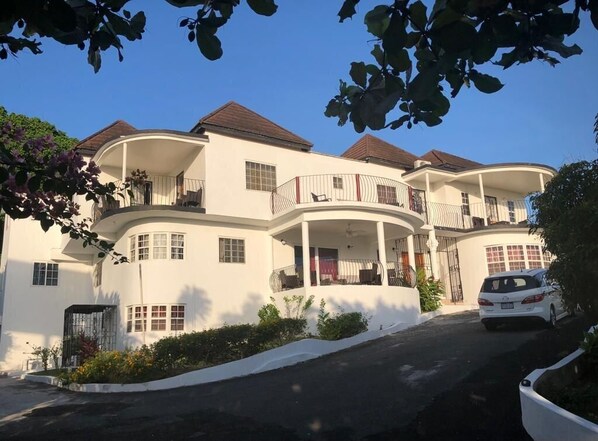 A multi-story white building with balconies, a covered driveway, and a parked car. - Upscale, Large country estate overlooking Spring Valley & the Caribbean Sea (Tower Isle)