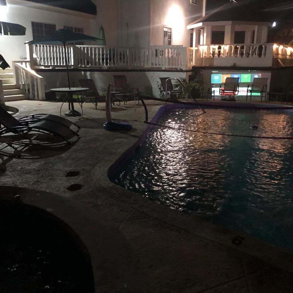 Zona de piscina al aire libre con sillones de descanso y un área de estar techada.