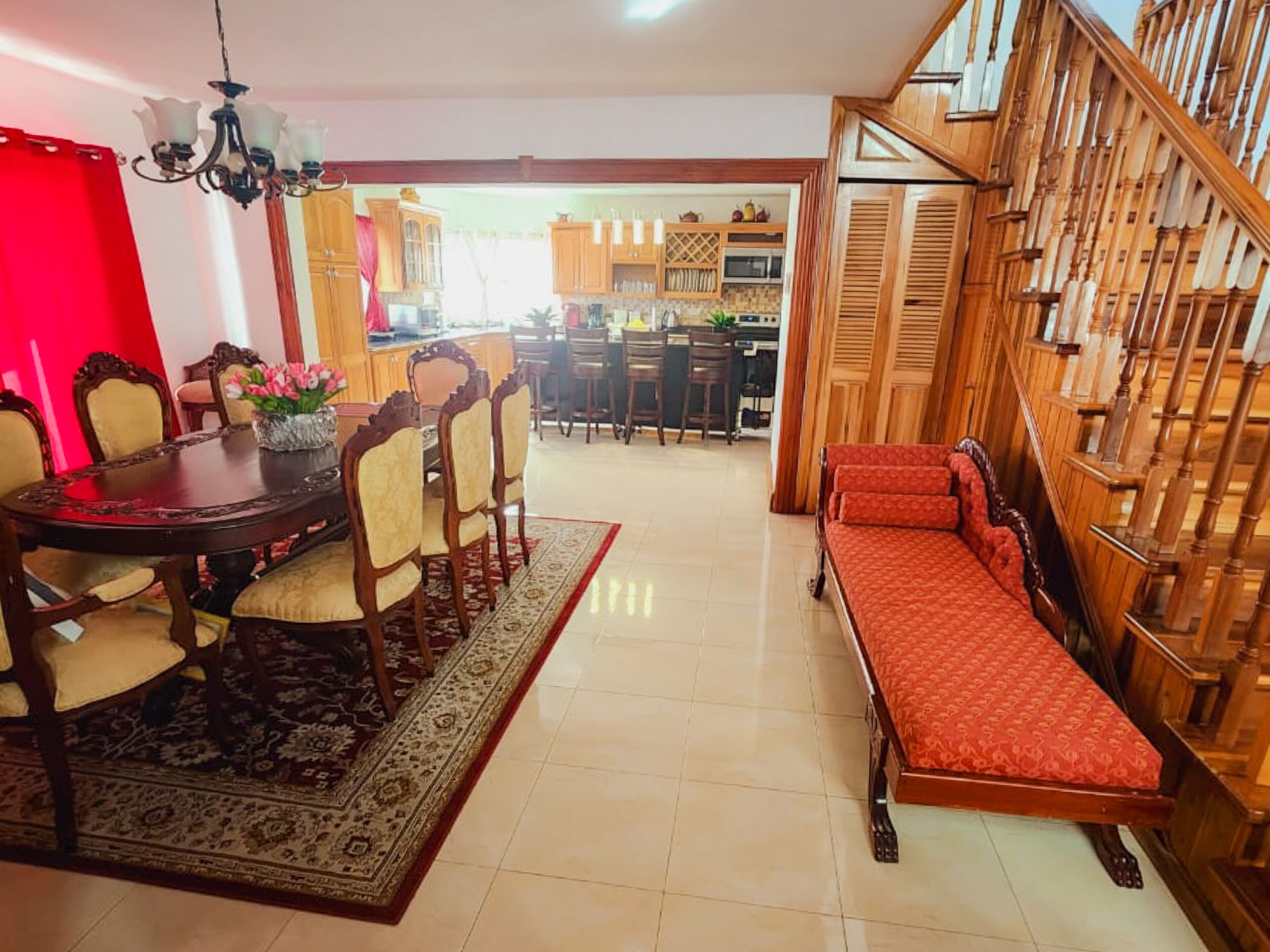 A dining area with a wooden table and chairs, a bench, and a staircase with wooden railings.
