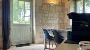 Una cocina rústica con pared de piedra, techo de madera, una mesa de comedor con sillas y un ventanal grande.