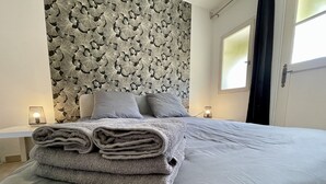 Una cama bien hecha con un edredón doblado, un papel tapiz estampado y dos lámparas de noche.