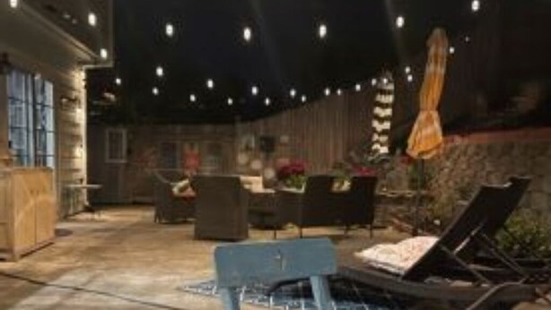 Un espace extérieur aménagé en terrasse, avec des fauteuils, une table et un tapis à motifs.