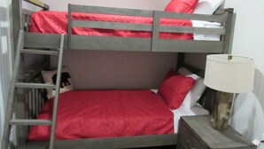 A bunk bed with red bedding, a bedside lamp, and a small wooden nightstand. - Arrowhead Lake Camp - Black Bear Lodge Lake View (Lupton)