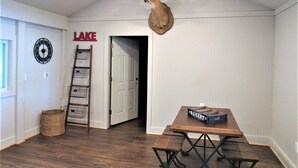 A room with a wooden floor, a wall-mounted clock, a sign reading "LAKE", a wooden bench, and a deer head mounted on the wall. - Arrowhead Lake Camp - Black Bear Lodge Lake View (Lupton)