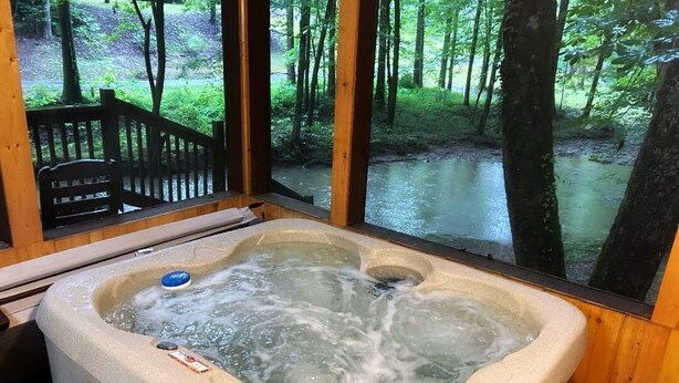 Ein Whirlpool mit Blick auf einen Wald und einer Holzterrasse.