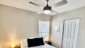 A bedroom with a bed, a ceiling fan, a window, and a door. - Home near the Beach w/ Hot-tub and Movie Room (Fort Pierce)