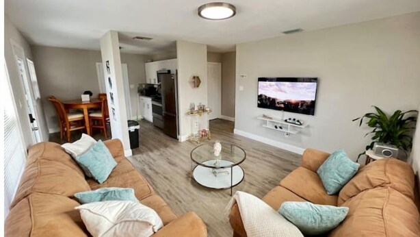 A modern living room with two sofas, a coffee table, and a TV. - Home near the Beach w/ Hot-tub and Movie Room (Fort Pierce)