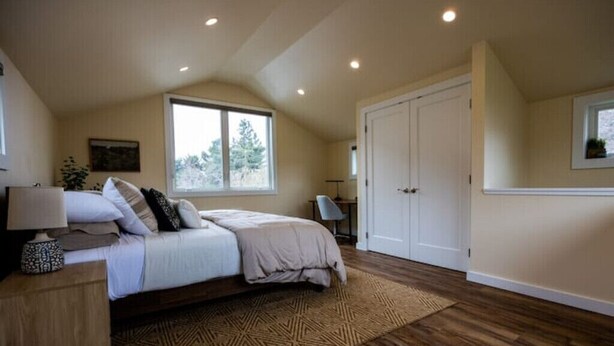 A bedroom with a bed, a nightstand, a window, and a door. - Greenough Loft (Missoula)