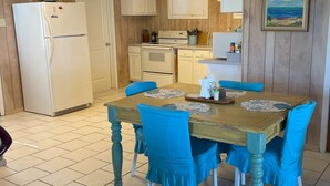 Una cocina con una mesa de madera y sillas azules, un refrigerador y una estufa.