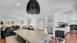 Une cuisine moderne avec des meubles blancs, un four à micro-ondes et une cuisinière. On y trouve également un coin repas avec une table et des bancs en bois.