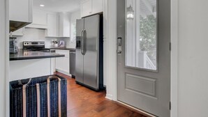 Une cuisine moderne avec des meubles blancs, un réfrigérateur en acier inoxydable et un plan de travail noir.