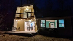 A two-story house with a balcony, a covered patio, and a visible interior with a door and windows. - Sugarloaf Golf Course View in the Heart of Leelanau County (Cedar)
