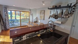 A kitchen with a large island, a sink, and a window overlooking a patio. - Sugarloaf Golf Course View in the Heart of Leelanau County (Cedar)