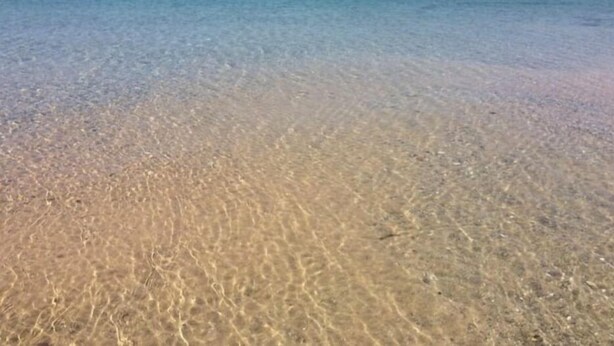 A beach with clear shallow water and a distant shoreline. - Sugarloaf Golf Course View in the Heart of Leelanau County (Cedar)