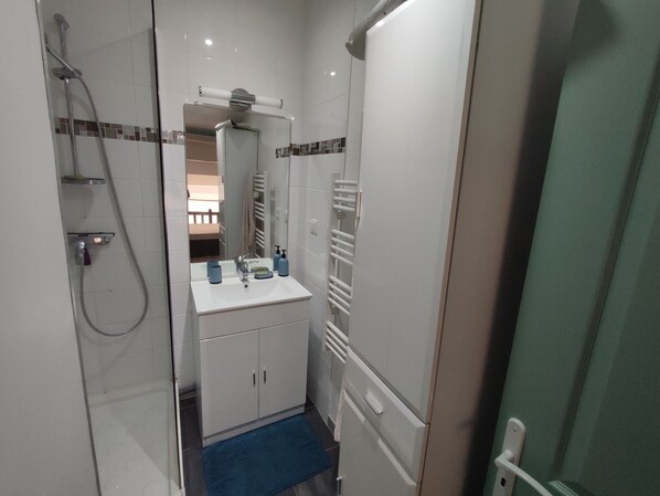 A compact bathroom with a shower, sink, and storage cabinets.