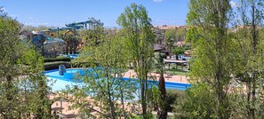 A resort with a swimming pool, palm trees, and a water park.