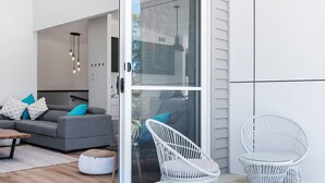 A modern living room with a grey sofa, white cushions, a wooden coffee table, and wicker chairs. - SeaSalt By The Sea Narrawallee (Narrawallee)