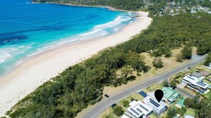 Enjoy a serene beach experience with clear waters and lush surroundings.