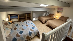 Een compacte slaapkamer met twee bedden, een houten wandplank en een klein raam.
