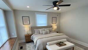 Una camera da letto con un letto, comodini, una ventola a soffitto e una finestra.