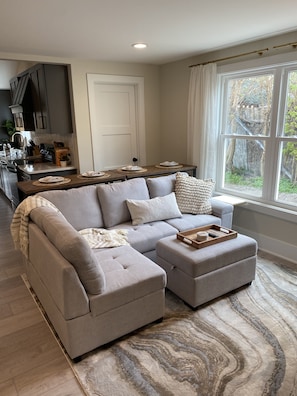A modern living room with a sectional sofa, a dining area, and a kitchen in the background. - Large Family Bungalow Sleeps 14, Close to Grand Park, Newly Renovated Private  (Sheridan)