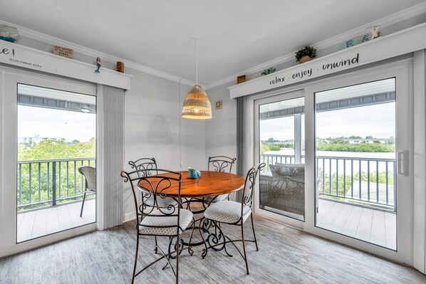 A dining area with a round table, chairs, and a hanging light fixture. - Waterfront End Unit Townhome with Garage(SS-23) (Indian Shores)