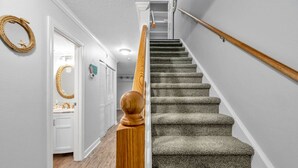 A staircase with a wooden handrail and carpeted steps leading to a landing.