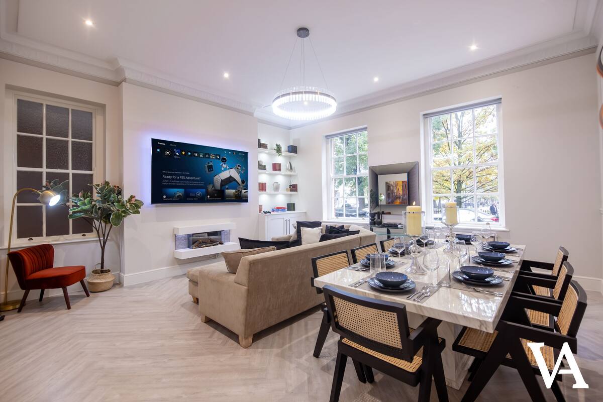 Un salon moderne avec un canapé, une table à manger dressée pour six personnes et un téléviseur fixé au mur.