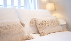 Una cama con ropa blanca y almohadas mullidas.