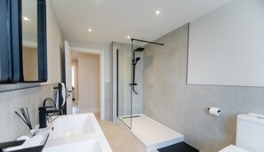 Un baño moderno con un lavabo grande de color blanco, una cabina de ducha de vidrio y un inodoro.