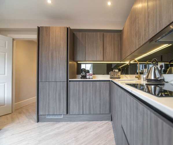 Una cocina moderna con armarios de madera, horno empotrado y hervidor de acero inoxidable.