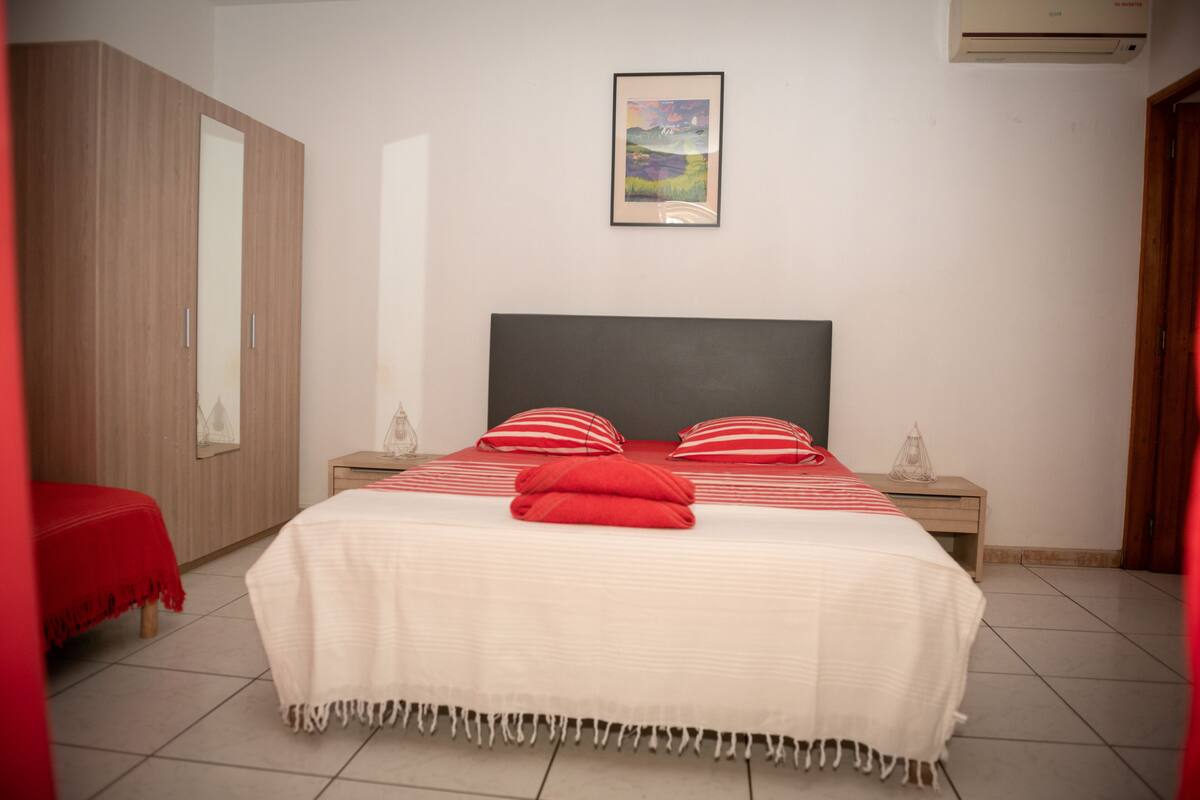 Un dormitorio con cama, dos mesitas de noche, un armario y un cuadro en la pared.