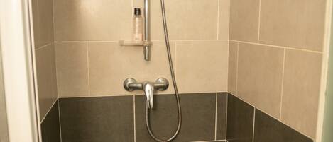 A shower with a handheld showerhead and a wall-mounted faucet.