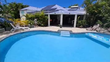 Una piscina al aire libre, sillones reclinables de piscina