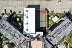 An aerial view of a building with a rooftop terrace, parking lot, and adjacent green spaces. - Barefootin'-Victorian-Gulf Front-Sleeps 6 (Galveston)