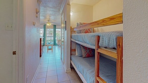 A narrow hallway with bunk beds, a ceiling fan, and a view through a door to an outdoor area. - Barefootin'-Victorian-Gulf Front-Sleeps 6 (Galveston)