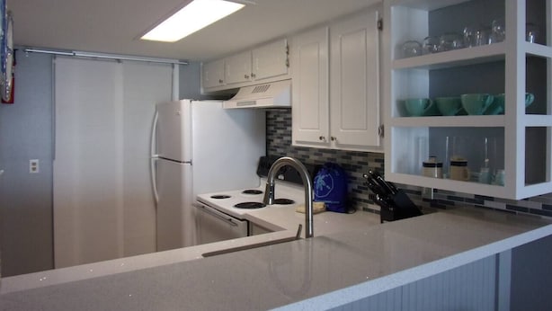 Una cocina moderna con armarios blancos, un refrigerador de acero inoxidable, una estufa empotrada y un lavaplatos.