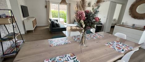 A modern dining area with a wooden table, white chairs, and floral placemats.