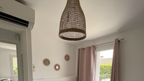 A bedroom with a large bed, a hanging light fixture, and a window with curtains.