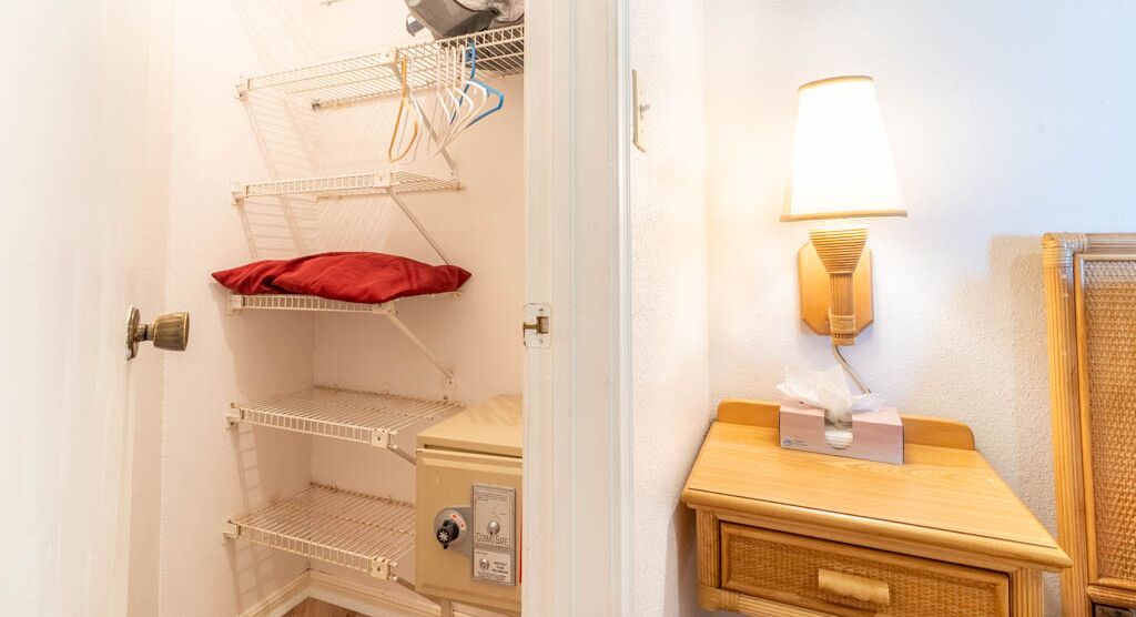 A storage closet with shelves and a small table with a lamp.