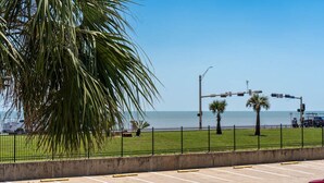A parking lot with a clear view of the ocean and a palm tree in the foreground.