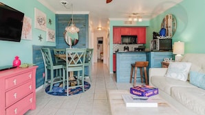 Uma sala de estar com sofá branco, mesa de centro e um espaço de jantar com mesa e cadeiras.
